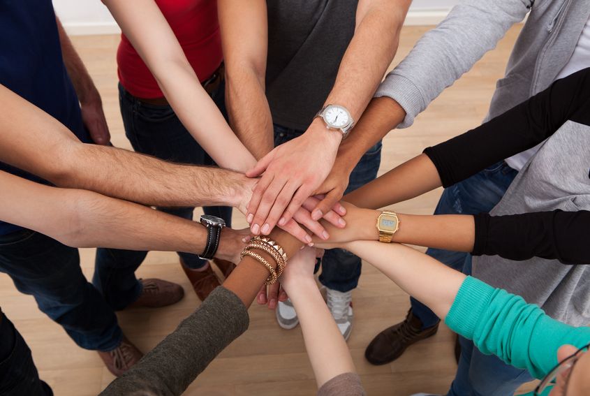 26835597 - high angle view of multiethnic college students stacking hands in classroom